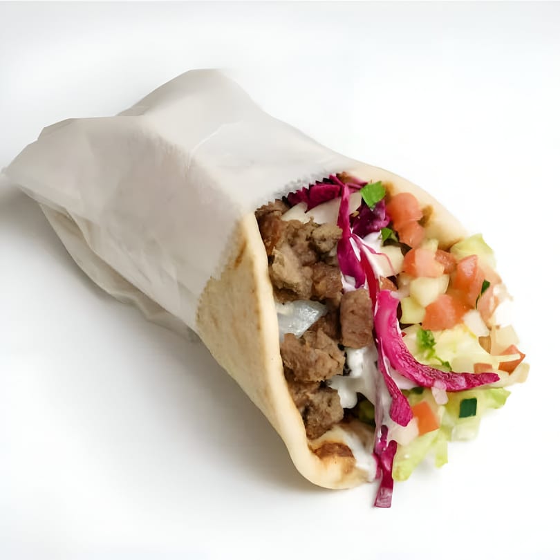 Halal gyro sandwich with meat, white sauce, red cabbage, and diced vegetables in pita bread.